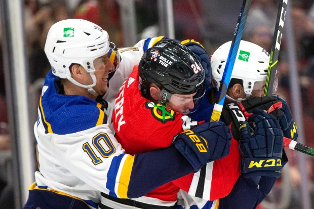 Blues forwards Brayden Schenn (10) and Jordan Kyrou, right, battle Blackhawks center Sam Lafferty against the boards on Feb. 27, 2022, at the United Center.  (Erin Hooley/Chicago Tribune)