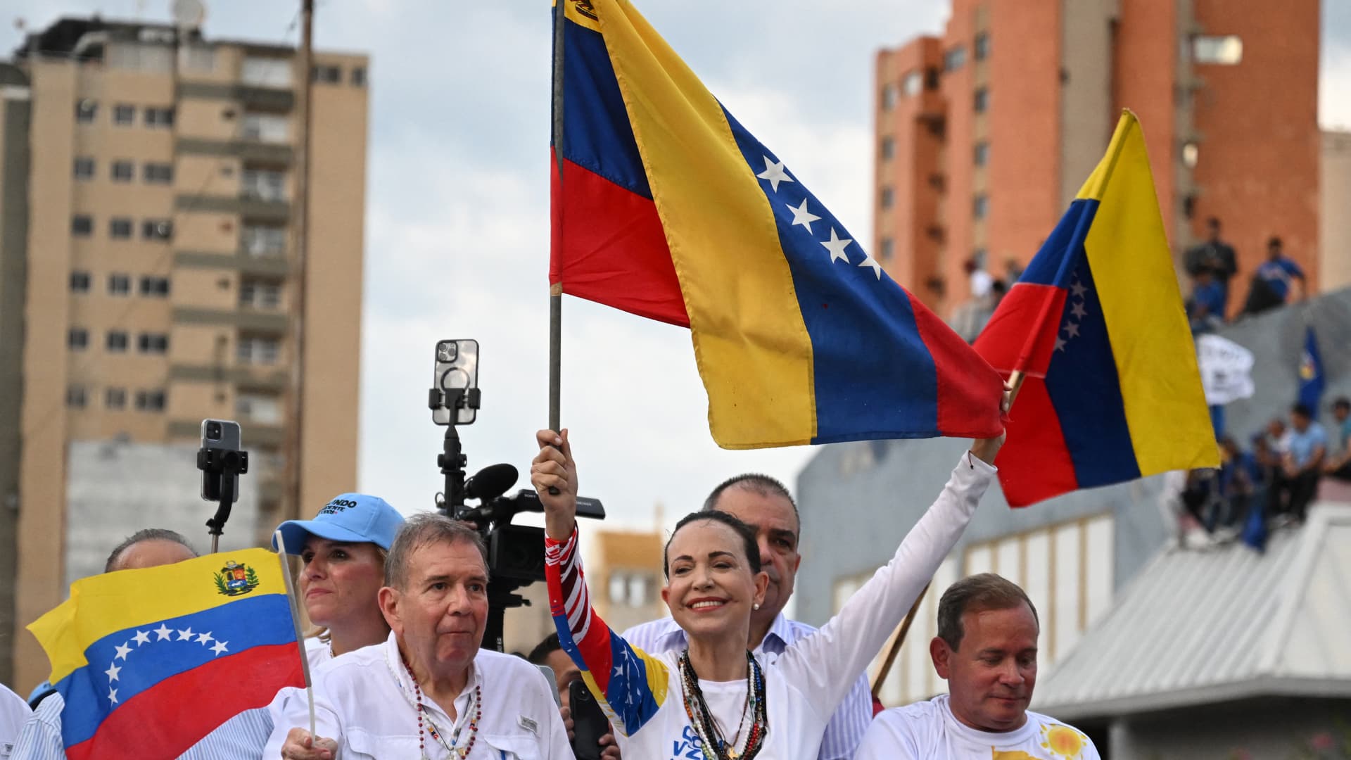 Venezuelan opposition presidential candidate Edmundo Gonzalez Urrutia and opposition leader Maria Corina Machado hold Venezuelan flags during a campaign rally in Maracaibo, Zulia state, Venezuela on July 23, 2024.